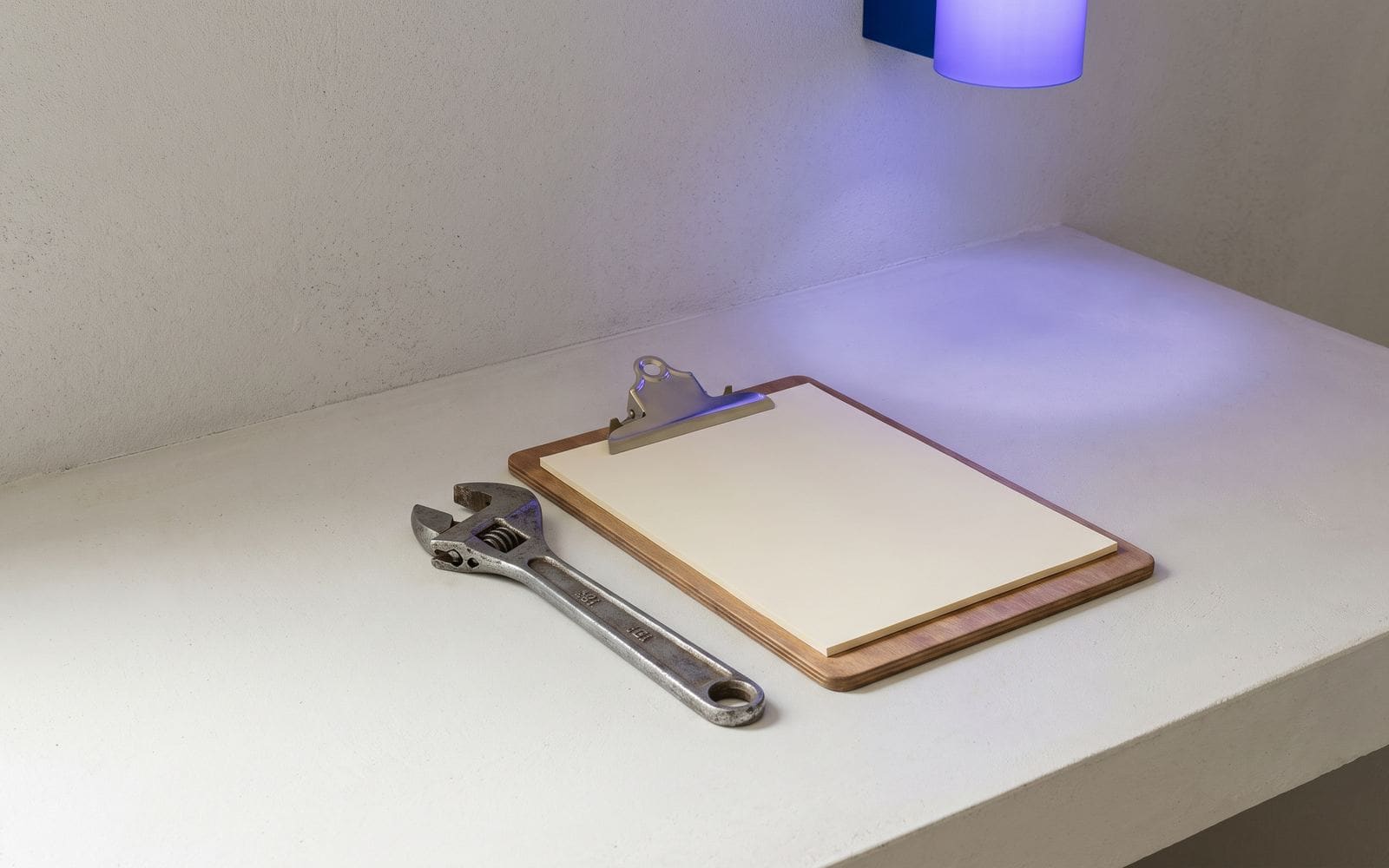 A wrench and a clipboard holding a blank form on a counter