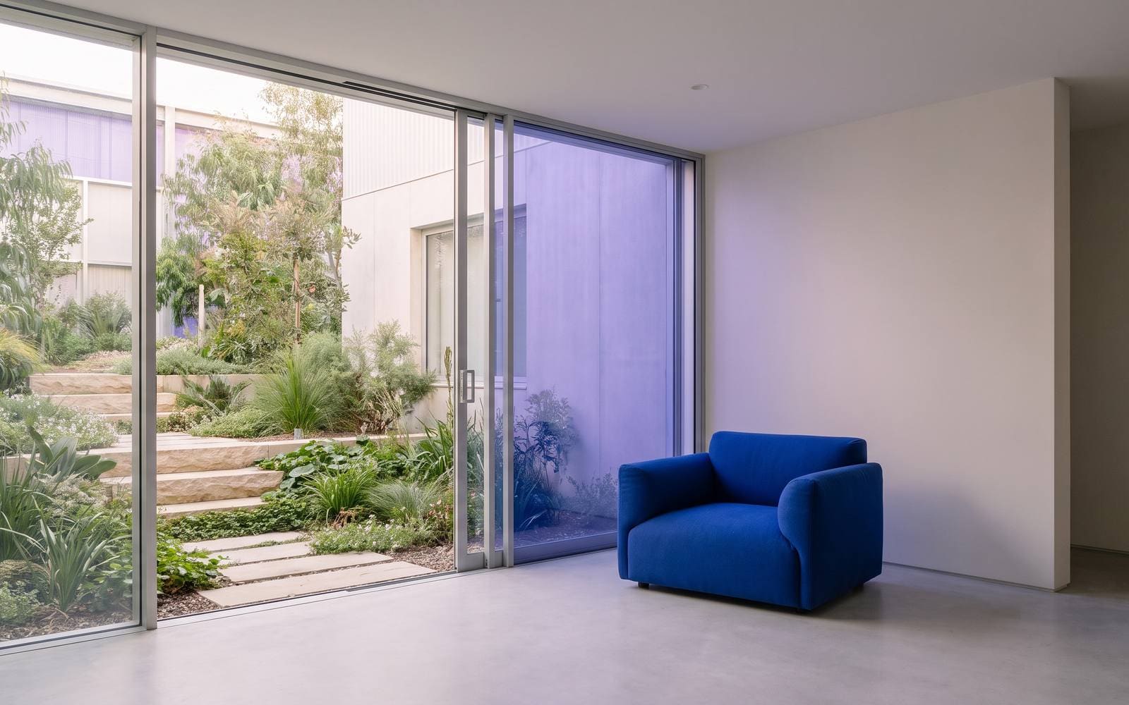 An apartment leasing lounge opening onto a courtyard through floor-to-ceiling glass