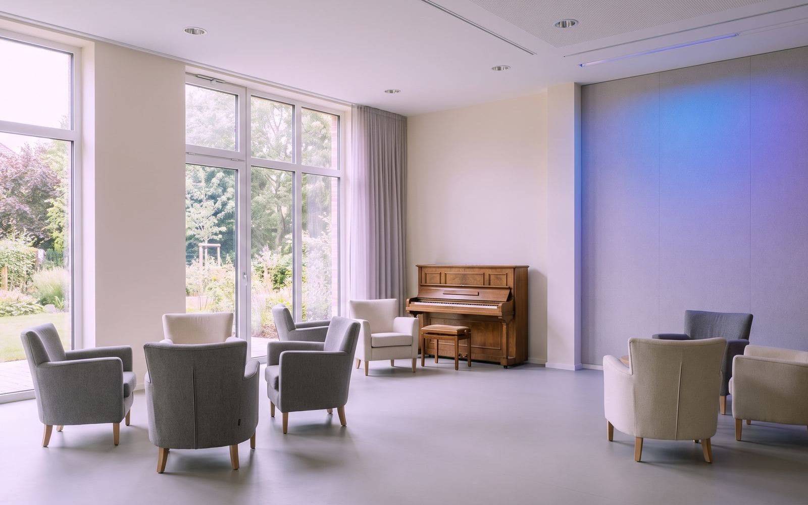 A bright common room with armchairs and garden windows